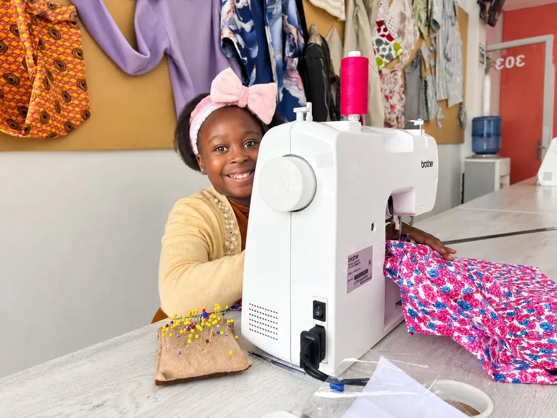 A girl smiling at her sewing machine at Sew & Grow