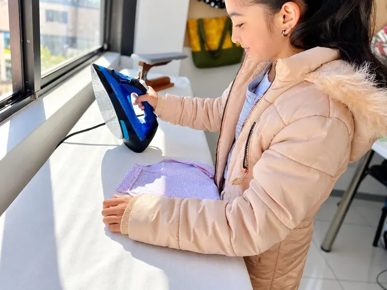 A child pressing her finished sewing project