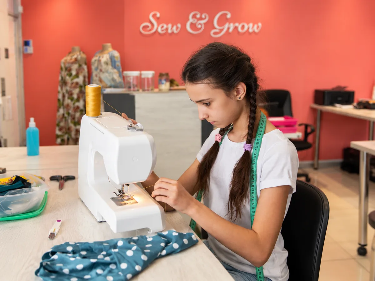 A girl sewing in the Sew & Grow studio