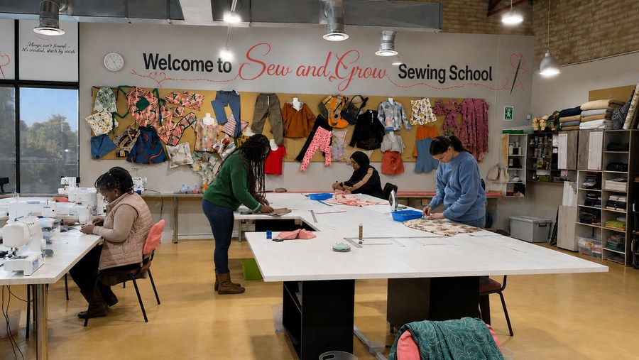 Students at work in the Sew and Grow studio under the welcome sign