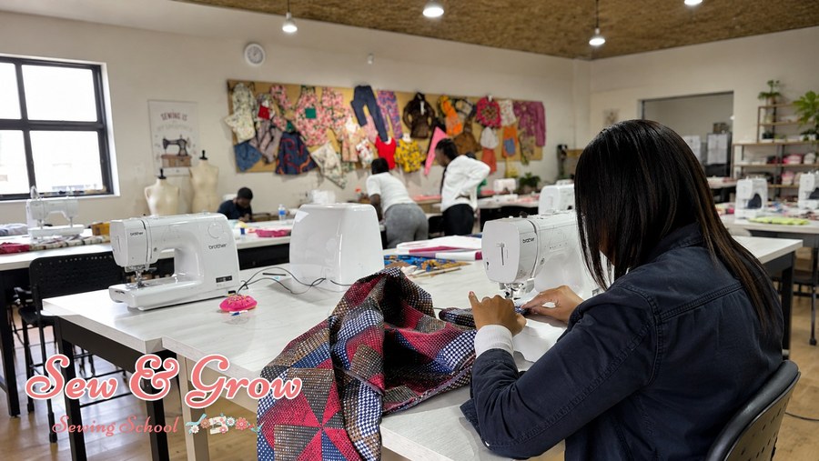 A student sewing colourful patchwork at her machine in class