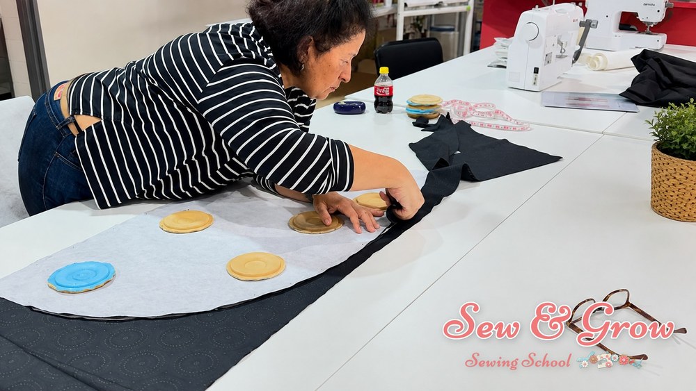 A student laying out pattern pieces on black fabric