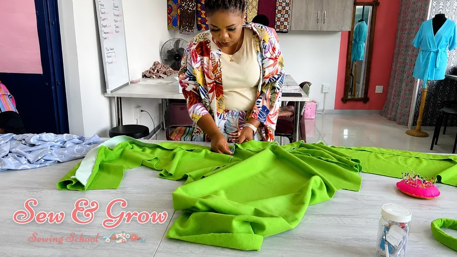 A student smoothing out bright green fabric before cutting