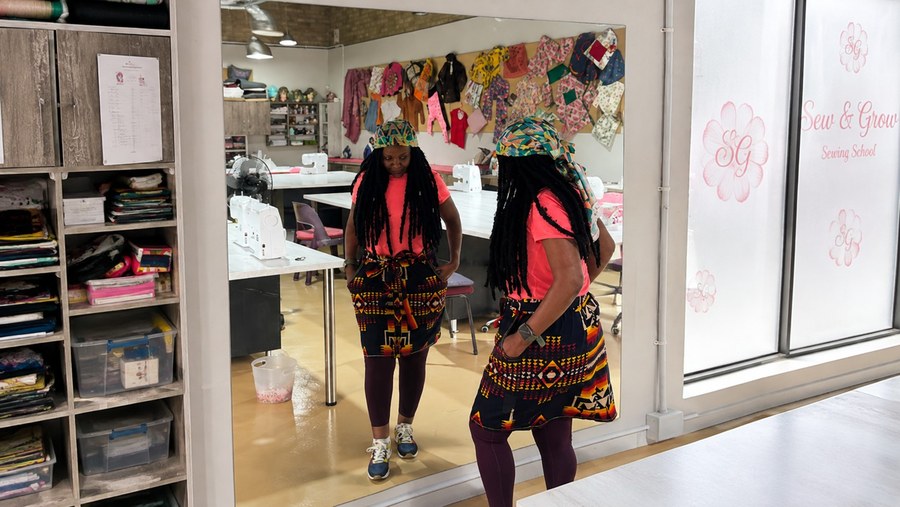 A student admiring a wrap skirt she made in the studio mirror