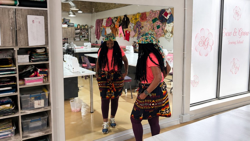A student admiring a wrap skirt she made in the studio mirror