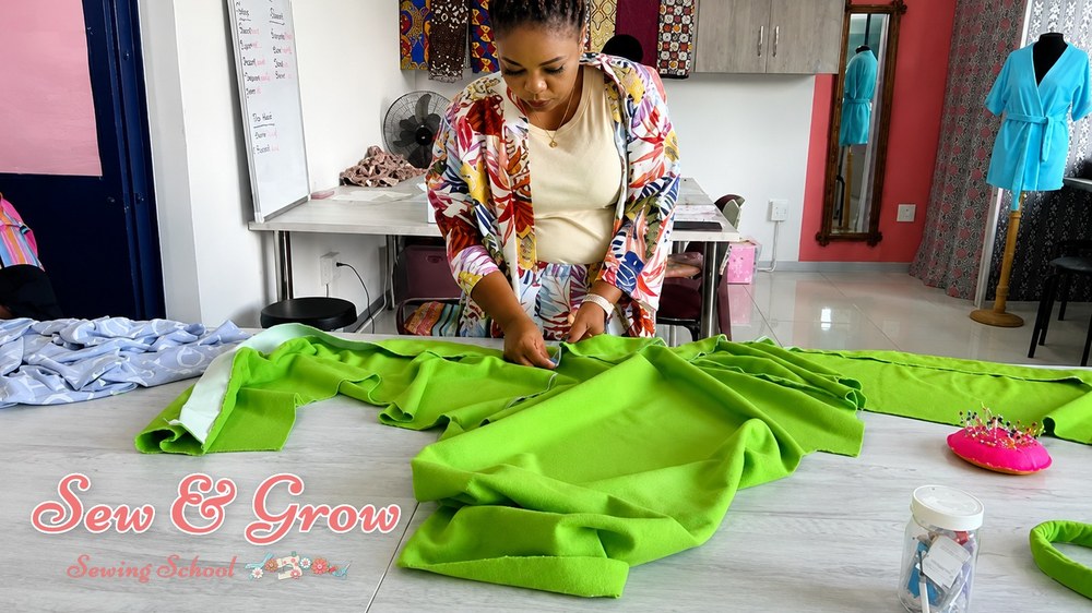 A student smoothing out bright green fabric before cutting