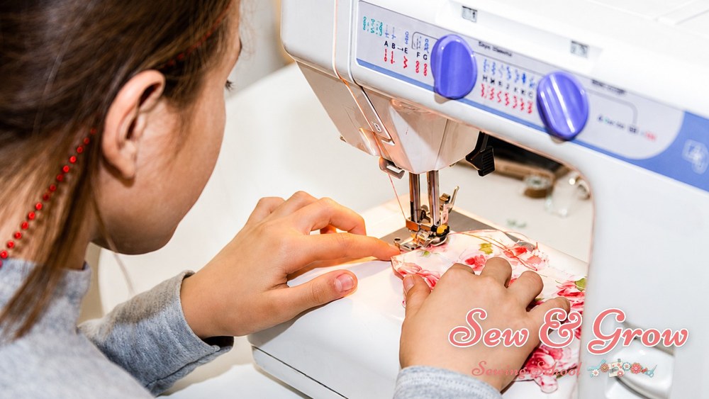 A learner guiding floral fabric carefully under the machine needle
